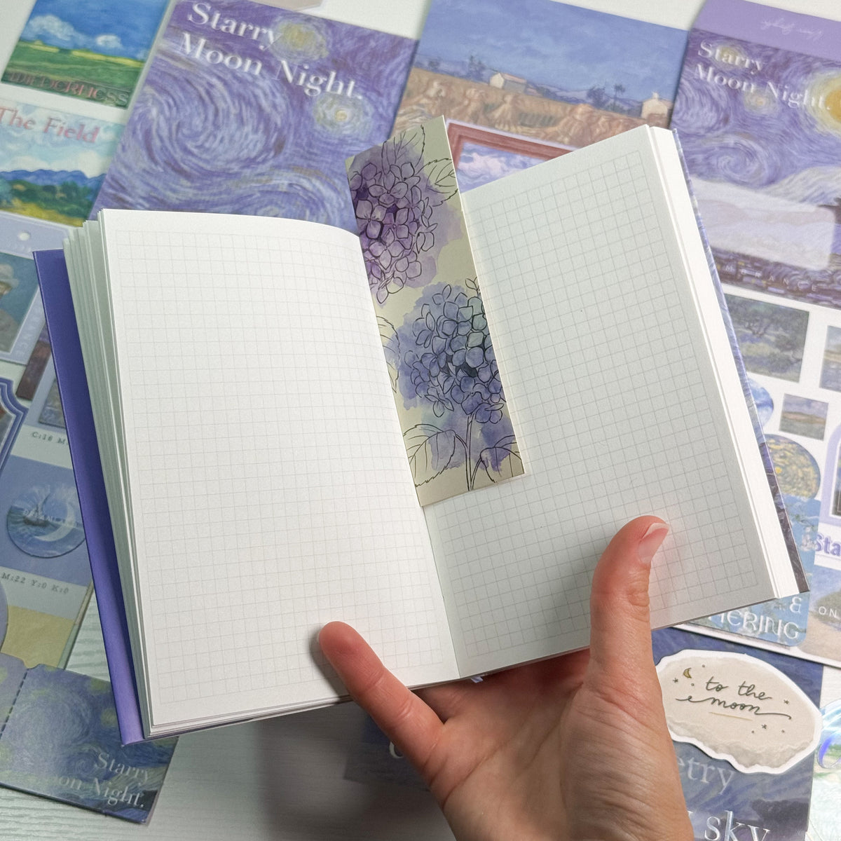 Starry Night journal open showing grid pages with hydrangea bookmark